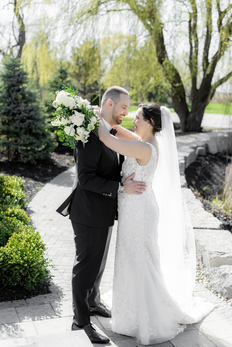 A newlywed couple embracing outdoors on a sunny day.