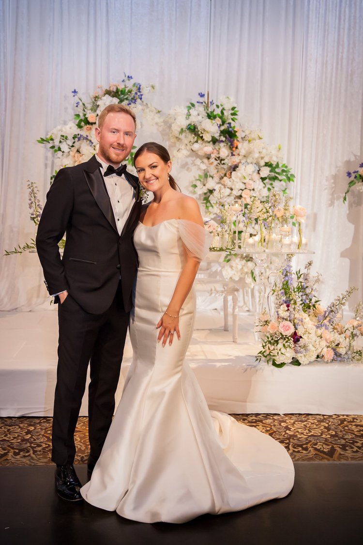 Bride and groom with floral wedding backdrop