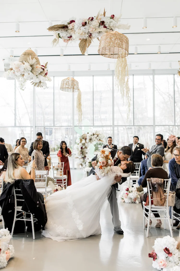 A wedding ceremony with a bride and groom sharing a kiss as the groom dips the bride.