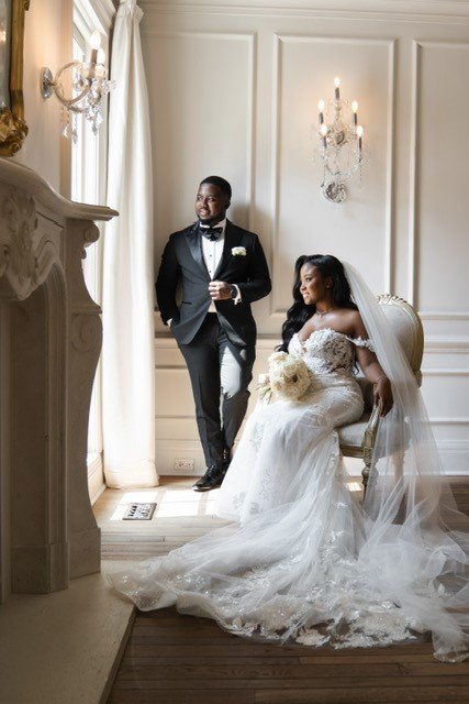 A newlywed couple in wedding attire in a luxurious, elegant room.