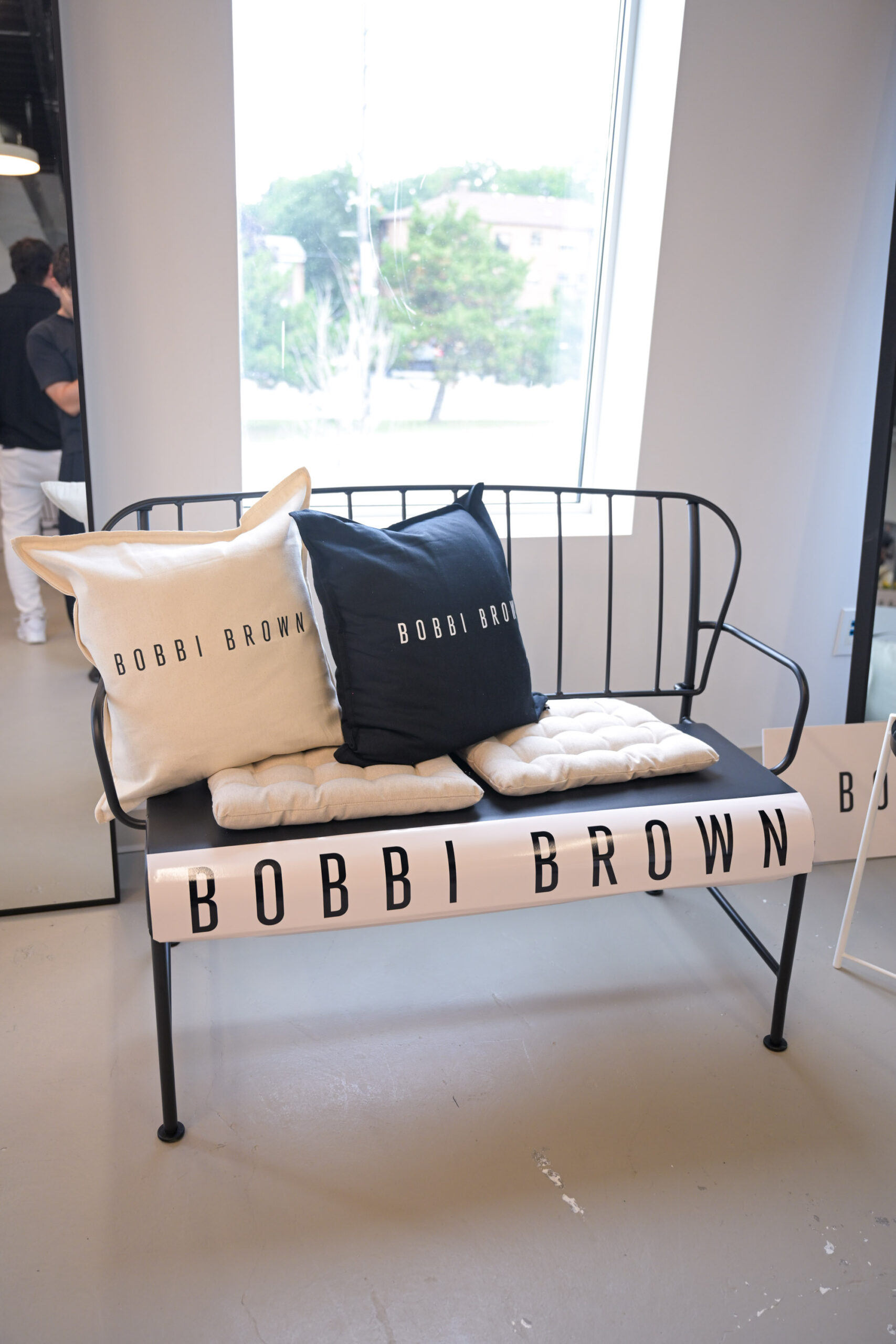 Black Bobbi Brown branded bench with cushions in the built event environment
