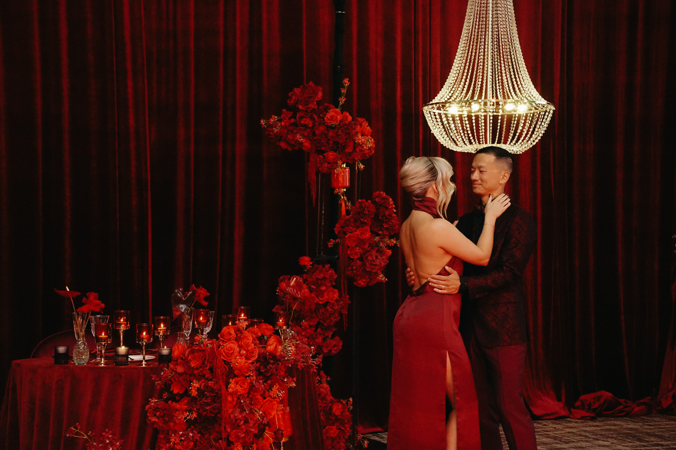 A couple sharing a quiet moment in a crimson wedding environment designed by Alexandria Design House